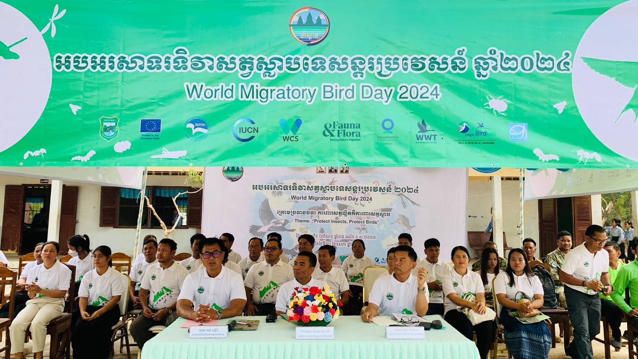 People sitting in rows behind a World Migratory Bird Day 2024 sign