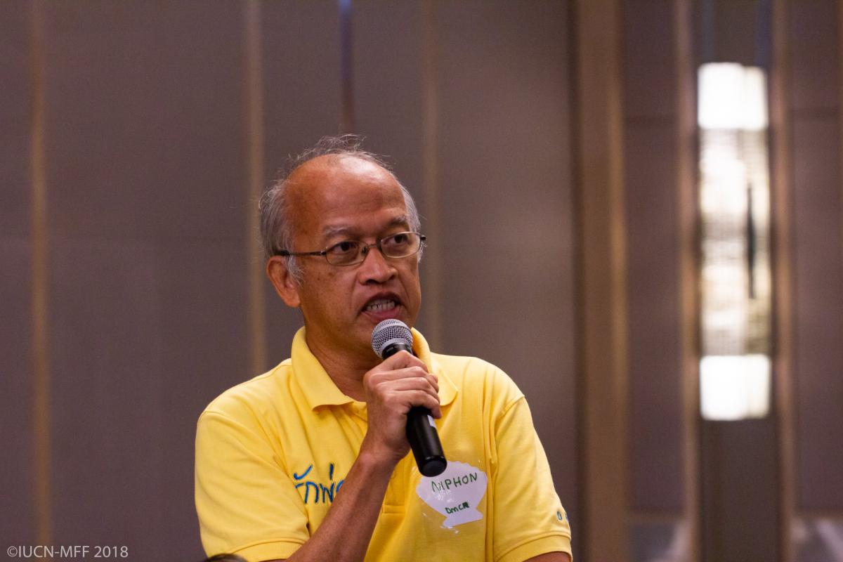 A man in a yellow shirt speaks into a microphone