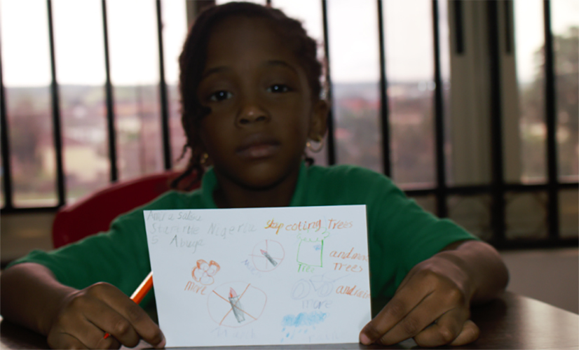 Child displaying her postcard during climate change education session in Nigeria. 