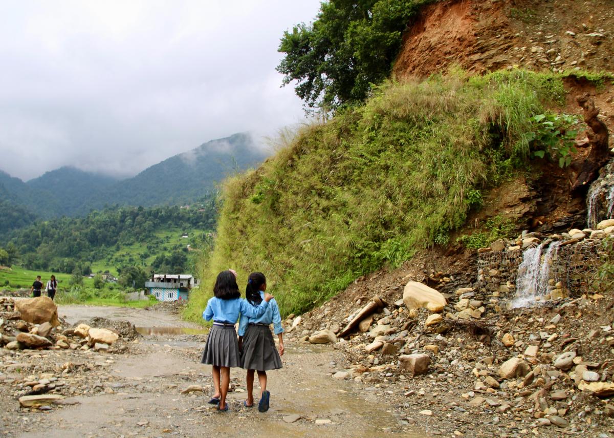 Two girls walk along a mountain road in Nepal