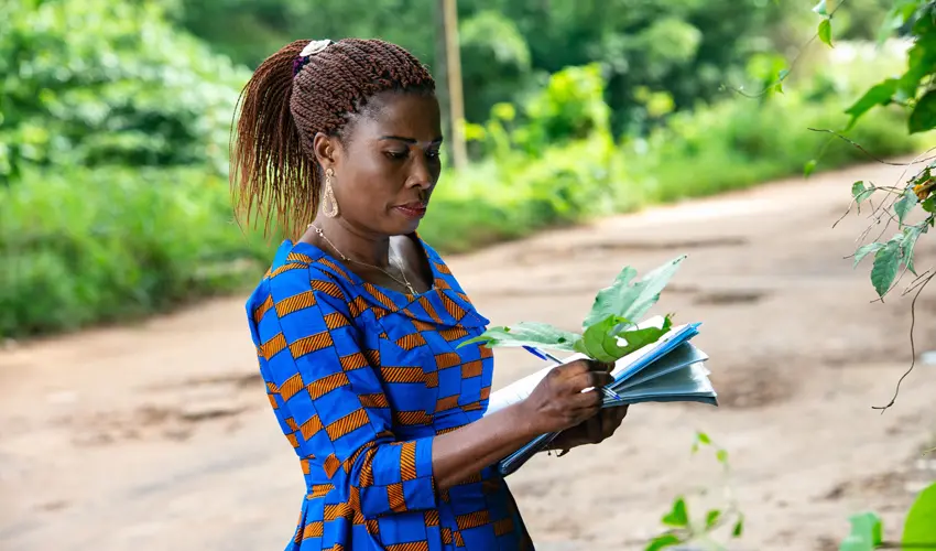 Woman examines leaf with clipboard