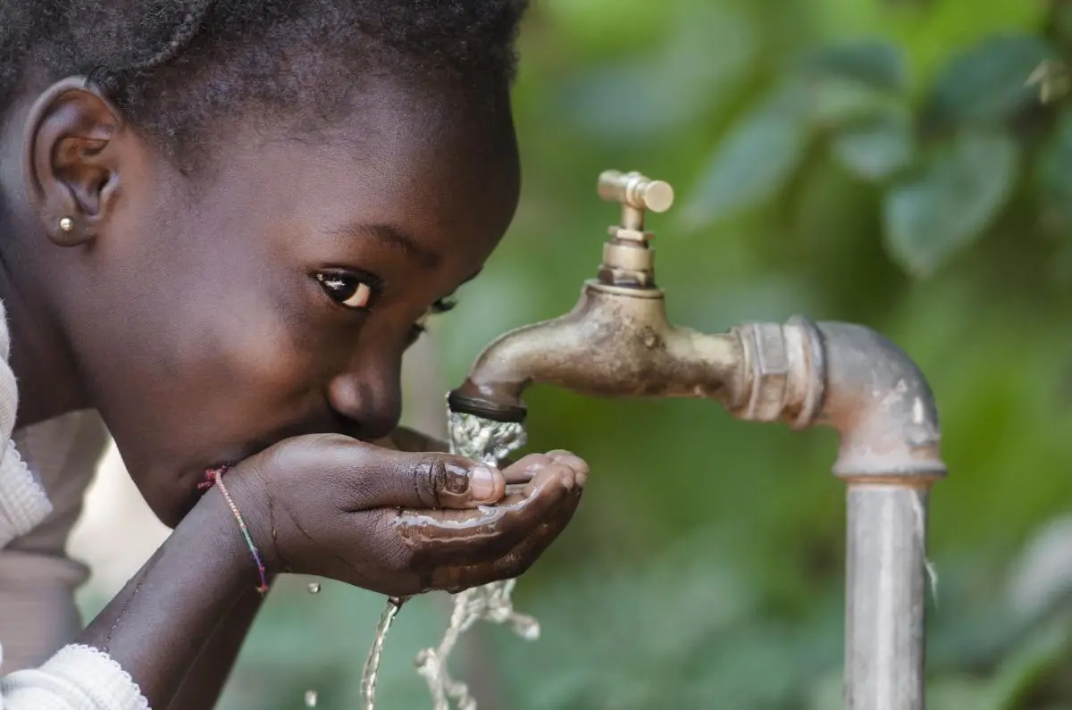 Girl drinking from a water tap in Bamako, Mali